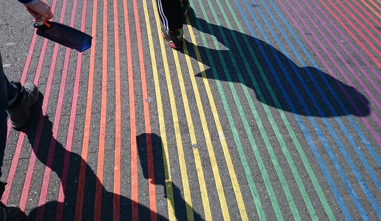 Shadows of people walking on rainbow sidewalk